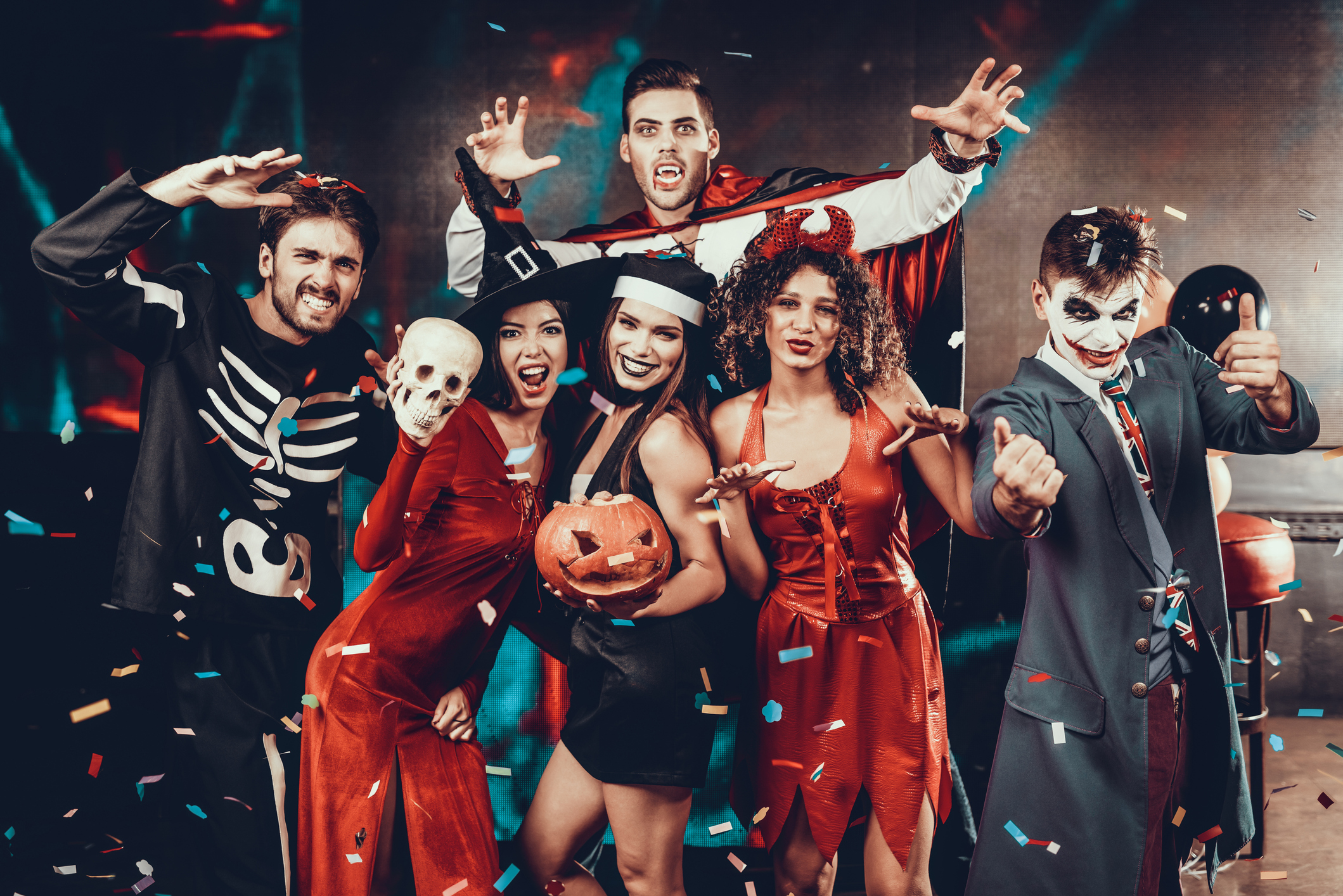 Portrait of Young Smiling People in Scary Costumes. Group of Young Happy Friends Wearing Halloween Costumes having Fun Together and posing for Group photo in Nightclub. Halloween Celebration